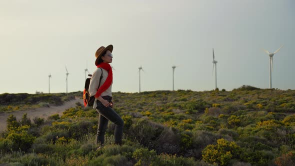 Young traveler woman with red scarf in front of green alternative energy turbines