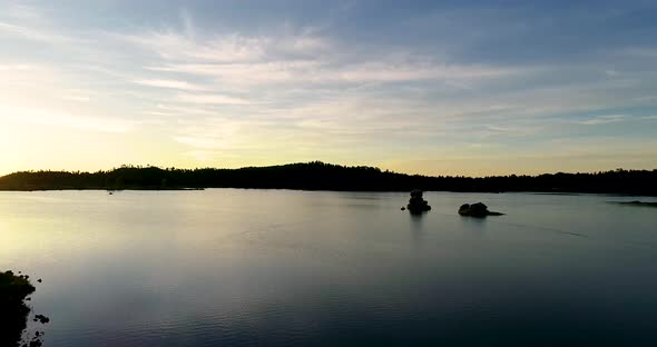 A serene aerial over a reflective lake in Colorado during a stunning sunrise.  Early morning light s