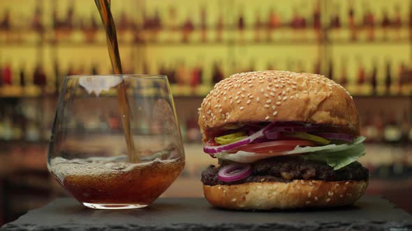 Pouring Coke Drink in the Glass with Burger on the Plate