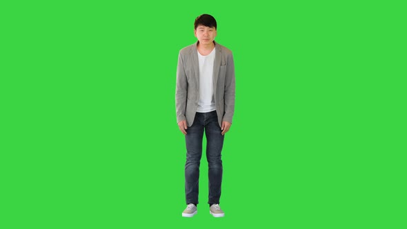 Young Asian Man in Casual Clothes Makes a Bow on a Green Screen Chroma Key