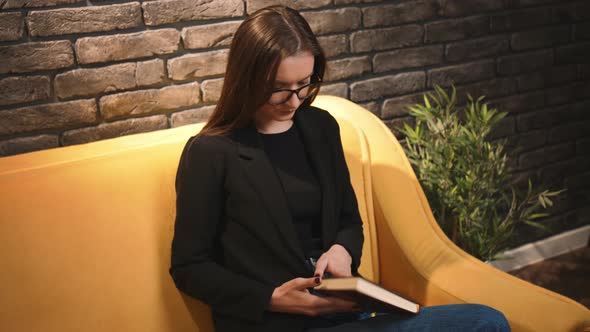 A Young Pretty Woman in Glasses Reading a Book Woman Yawning While Reading a Book at Home Office