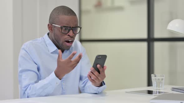 African Man Reacting Loss While Using Smartphone