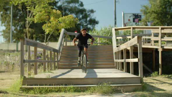 Front View of Focused Man with Bionic Leg Riding Bike in Park