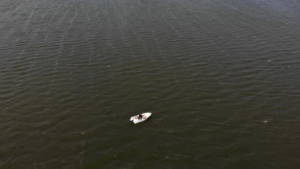 Lonely Man Fishing on a Boat in the Middle of River During Strong Winds