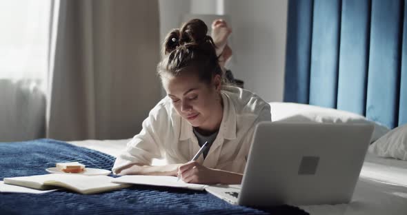 Female Student Using Laptop on Bed