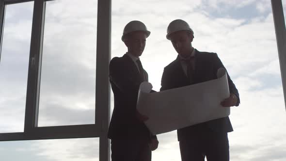 Site Managers Studying Blueprint before Panoramic Window