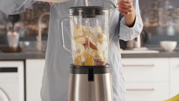 Close Up Footage of Female Adding Milk to Blender with Pieces of Fruits to Make Smoothie in