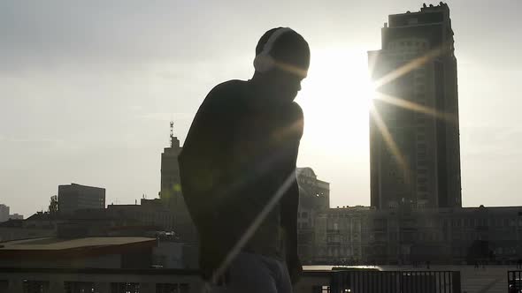 Silhouette of adult fighter warming up before match in rays of sun, motivation