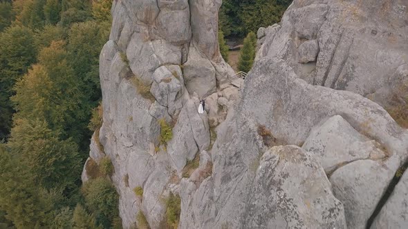 Newlyweds Stand on a High Slope of the Mountain. Groom and Bride. Aerial View