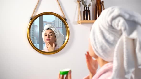 Woman Applying Creme on Face After Taking Shower