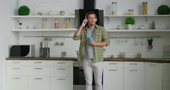 Young Confident Man Is Dancing and Listening Music in His Kitchen