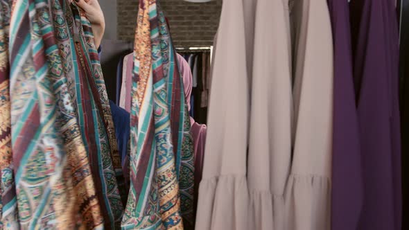 A Young Muslim Woman Choosing Clothes at the Store