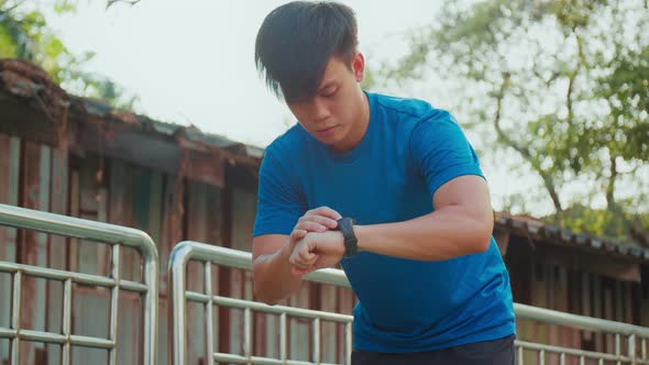 Active young male using smartwatch measuring heart rate during exercise.
