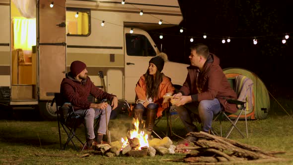 Group of Close Friends Laughing Together Around Camp Fire