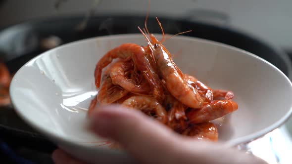 cook removing fried prawns from the heat during the preparation of fideua