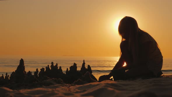 Silhouette of a Child Builds a Sand Castle on the Beach a Beautiful Sunset