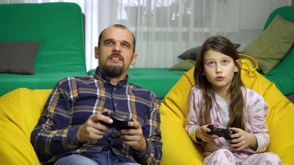 father and daughter playing gamepads together at home