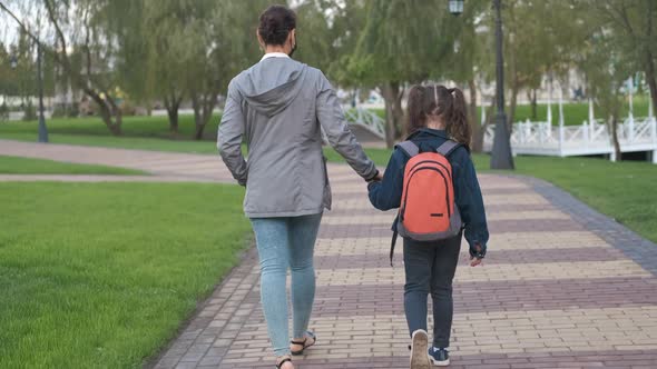 Mother leads the child to school.