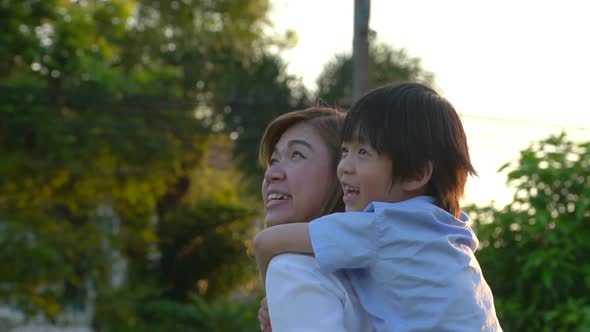 Asian Child On A Piggy Back Ride With His Mother Outdoor