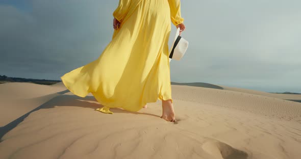 Close-up Woman in Yellow Stylish Fashion Dress Walking Barefoot By Rippled Dune