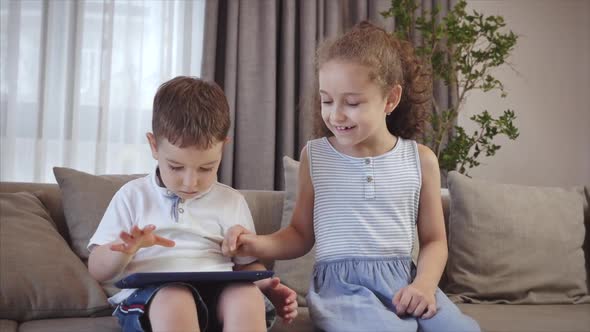 Cute Family and Daughter,sister-in-law a Nanny with Little Brother,looking at the Screen of a Tablet