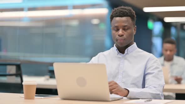 Attractive African Businessman Looking at Camera While Using Laptop in Office