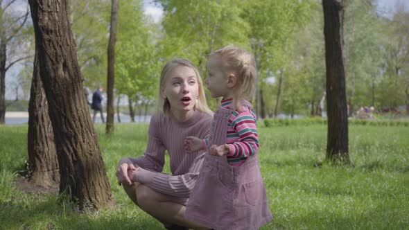 Cute Little Girl Playing in the Park with Her Mother, Pointing with Tiny Finger Away. Woman