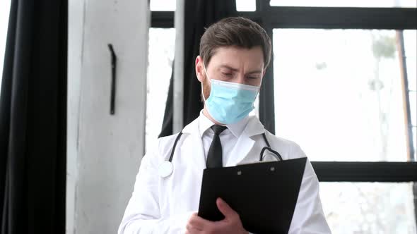 Caucasian Male Doctor Therapist Surgeon Cardiologist in a Medical Uniform Protective Mask and with