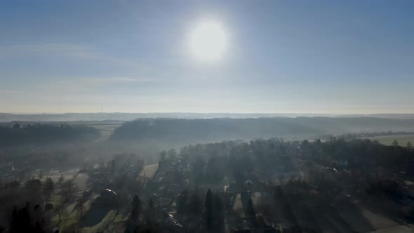 Aerial View of Forest and Farmland During Foggy and Cold Winter Morning with Blue Sky Facing the Sun