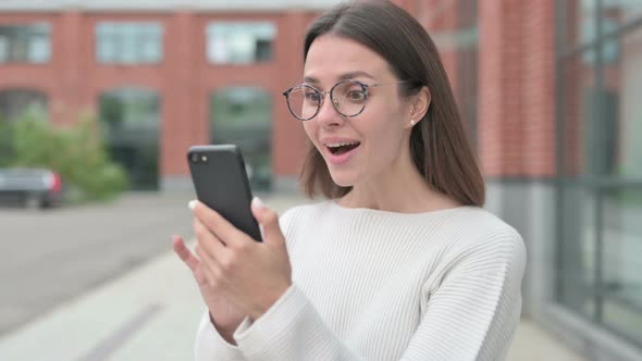 Woman Celebrating Success on Smartphone