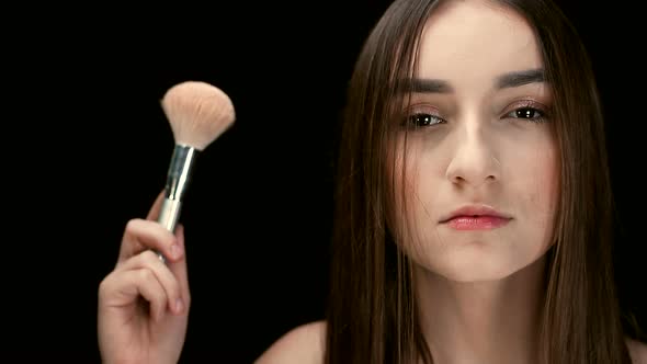 Fashion Model Girl Holds a Powder Brush in Her Hand and Shakes Off the Powder. Small Particles