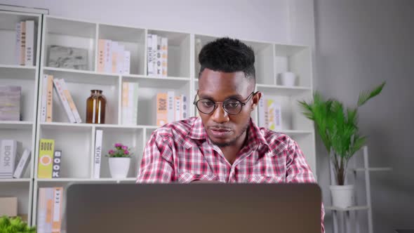 African man working from home and having a meeting with team by online application on laptop