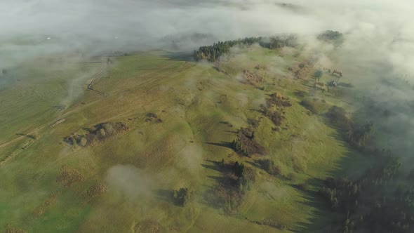 Aerial approach over misty landscape shrouded in fog