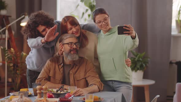 Joyous Family Taking Selfie with Smartphone at Dinner