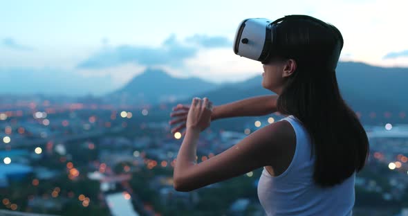 Woman watching on virtual reality device at sunset time 