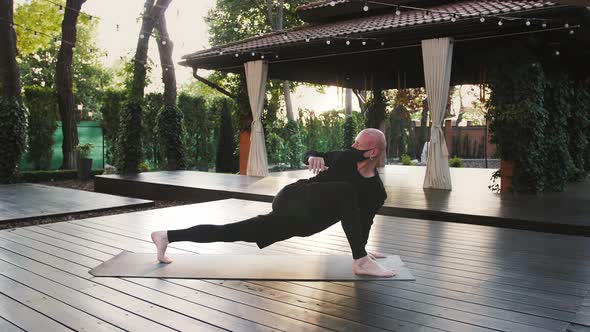 Strong Barefoot Guy in Black Protective Mask and Sport Clothes is Practicing Yoga on Mat in