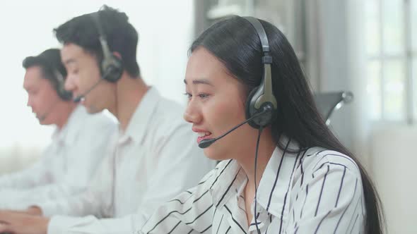 Close Up Of Three Asian Call Centre Agents Typing On Computer While Speaking To Customers