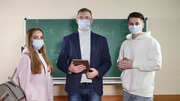 The Teacher and Students Stand Near the Blackboard and Remove the Protective Medical Masks After the