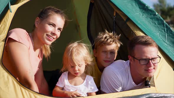 Young Family Who Sits in a Tent Watching the Distance to Nature People are Happy