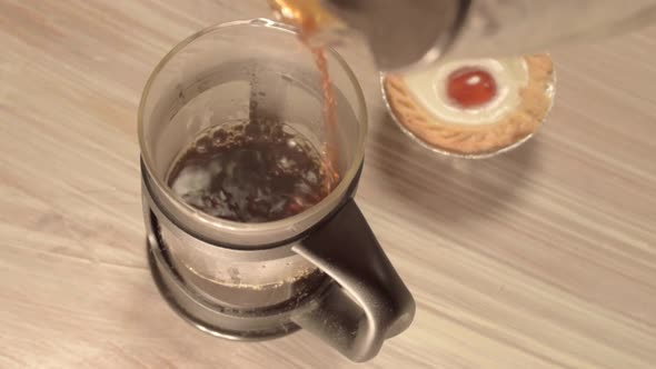 Pouring fresh coffee into a pot with cherry cake
