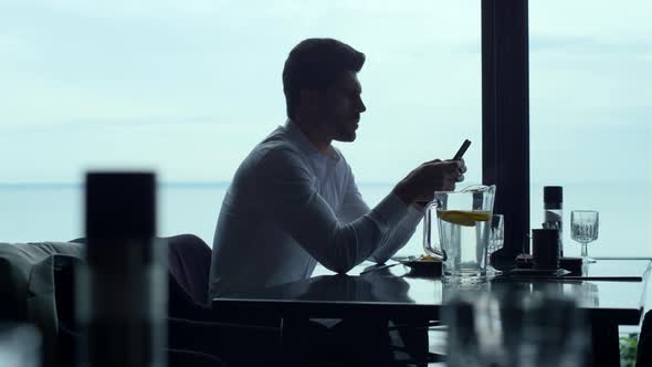 Busy Businessman Reading Message on Smartphone on Lunch in Luxury Restaurant