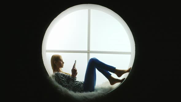 Student Lies Inside a Round Window Reads an Ebook