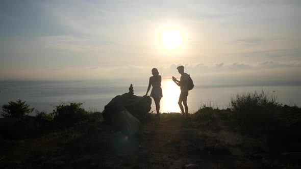 Unrecognizable Couple Taking Pictures on a Cliff Viewpoint at Sunrise.