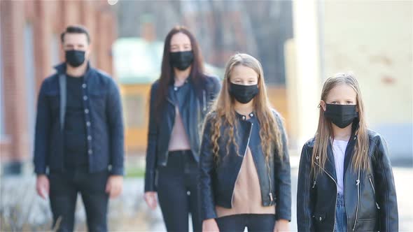 Family Wearing a Mask on a Background of a Modern Building