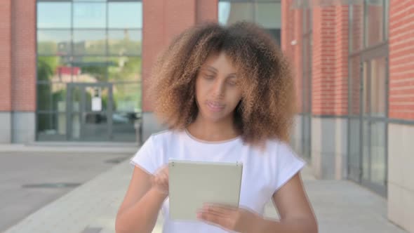 African Woman Browsing Internet on Tablet While Walking Outside