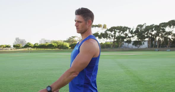 Smiling fit caucasian man exercising outdoors stretching from the waist