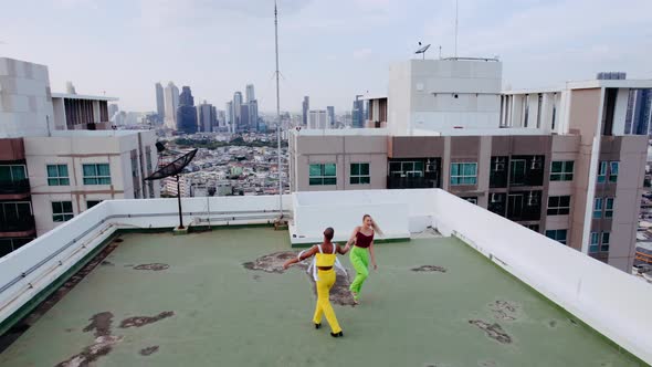 Drone Shot Of Models In Green And Yellow Dancing On City Rooftop