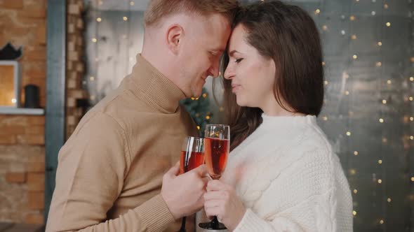 Couple in Love Dancing, Kissing Near the Christmas Tree and Drinking Champagne