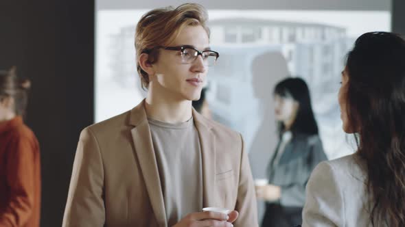 Young Man Talking with Female Colleague on Business Event