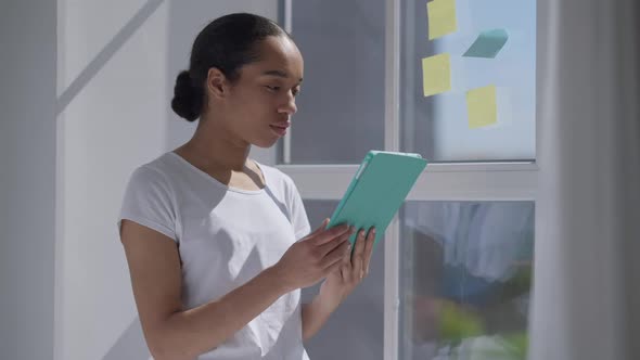 Sad Fatigued Worried African American Woman Wiping Forehead Looking at Tablet Screen Standing in